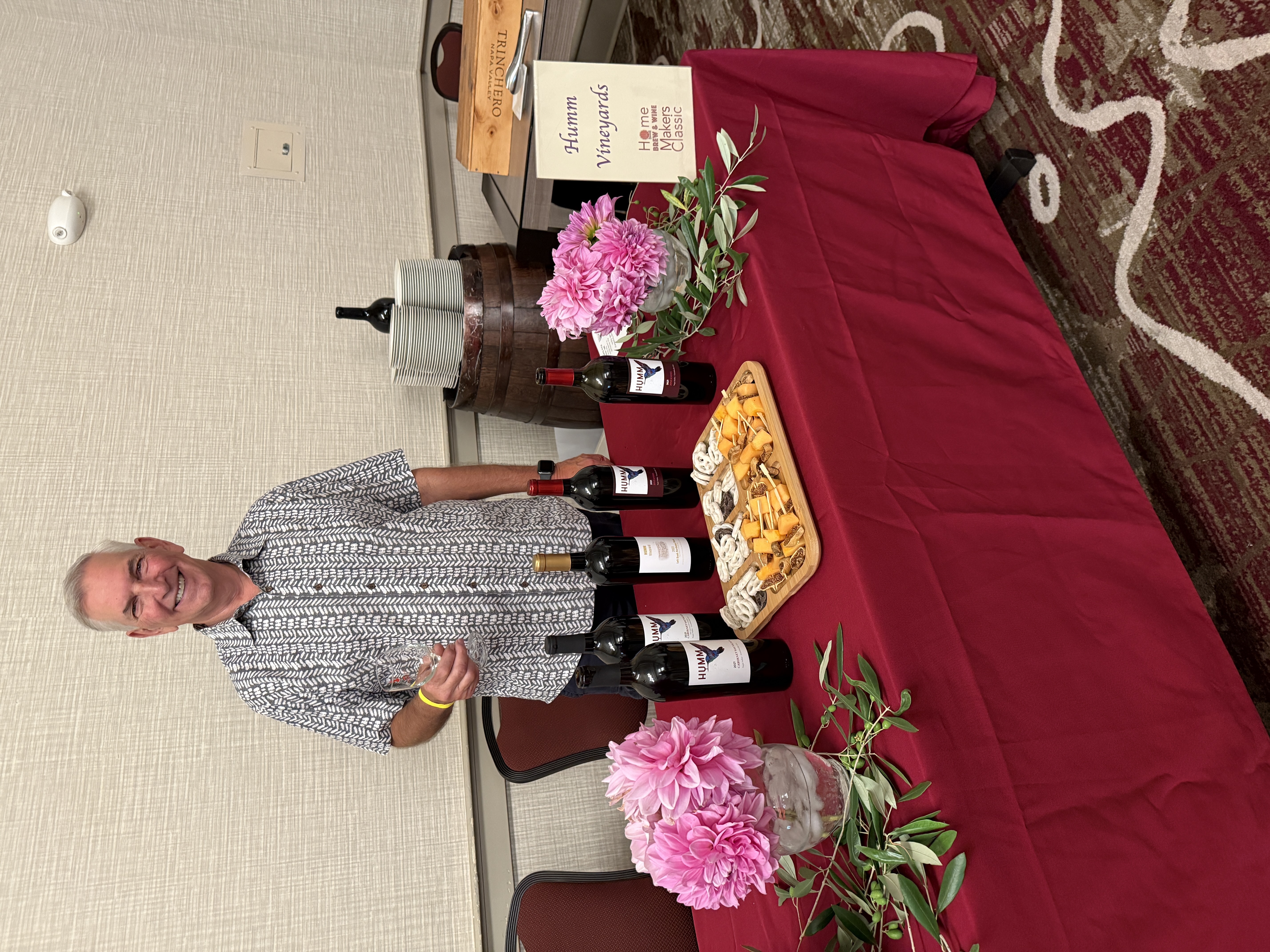 Humm Vineyards tasting table with wine bottles, cheese board, and pink flowers